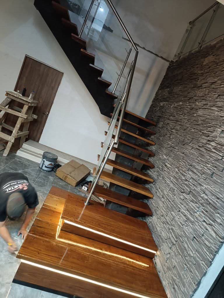 Escalera con baranda de vidrio y pared de piedra natural