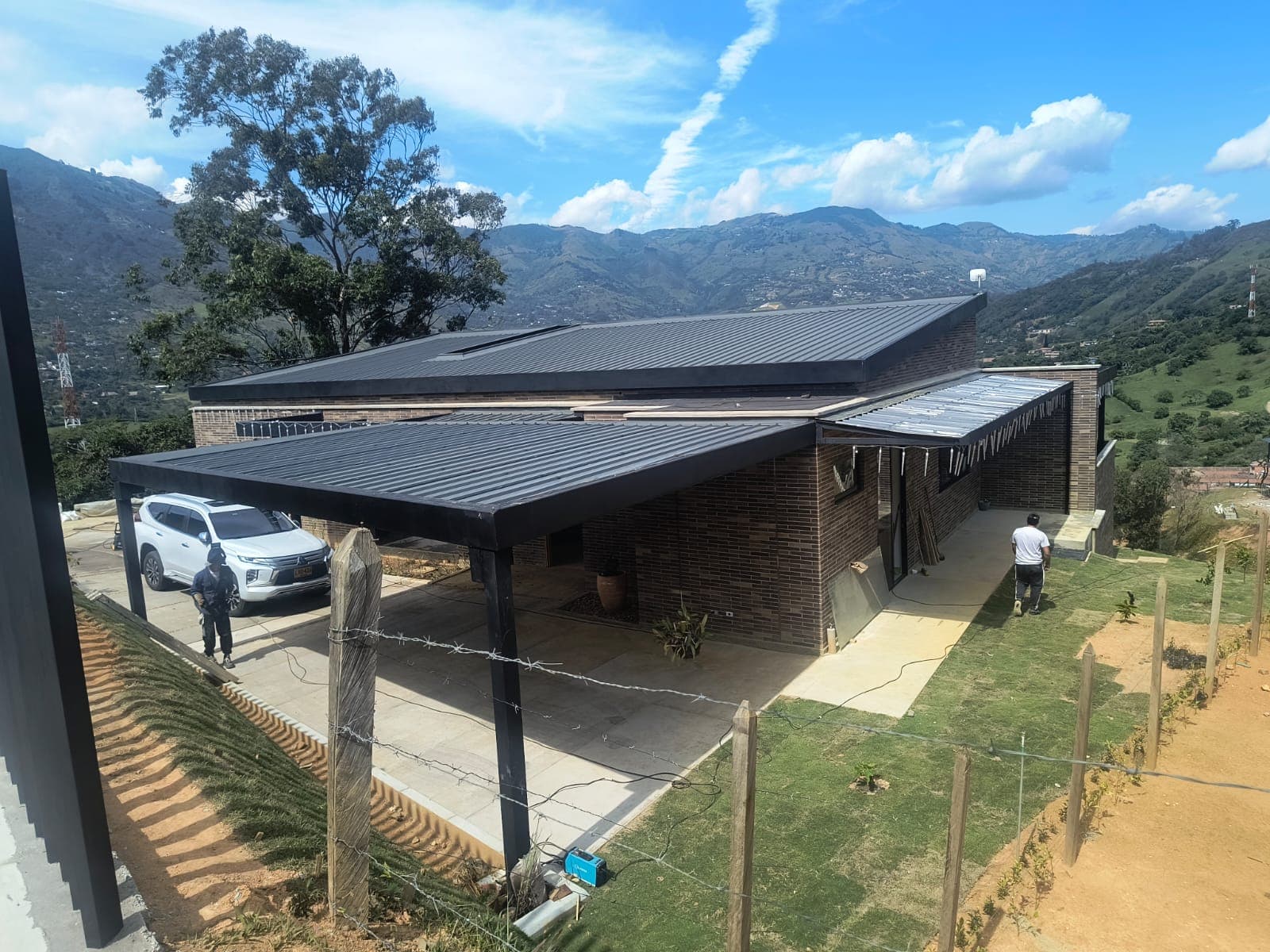 Casa mixta terminada con techo metálico y vista a las montañas