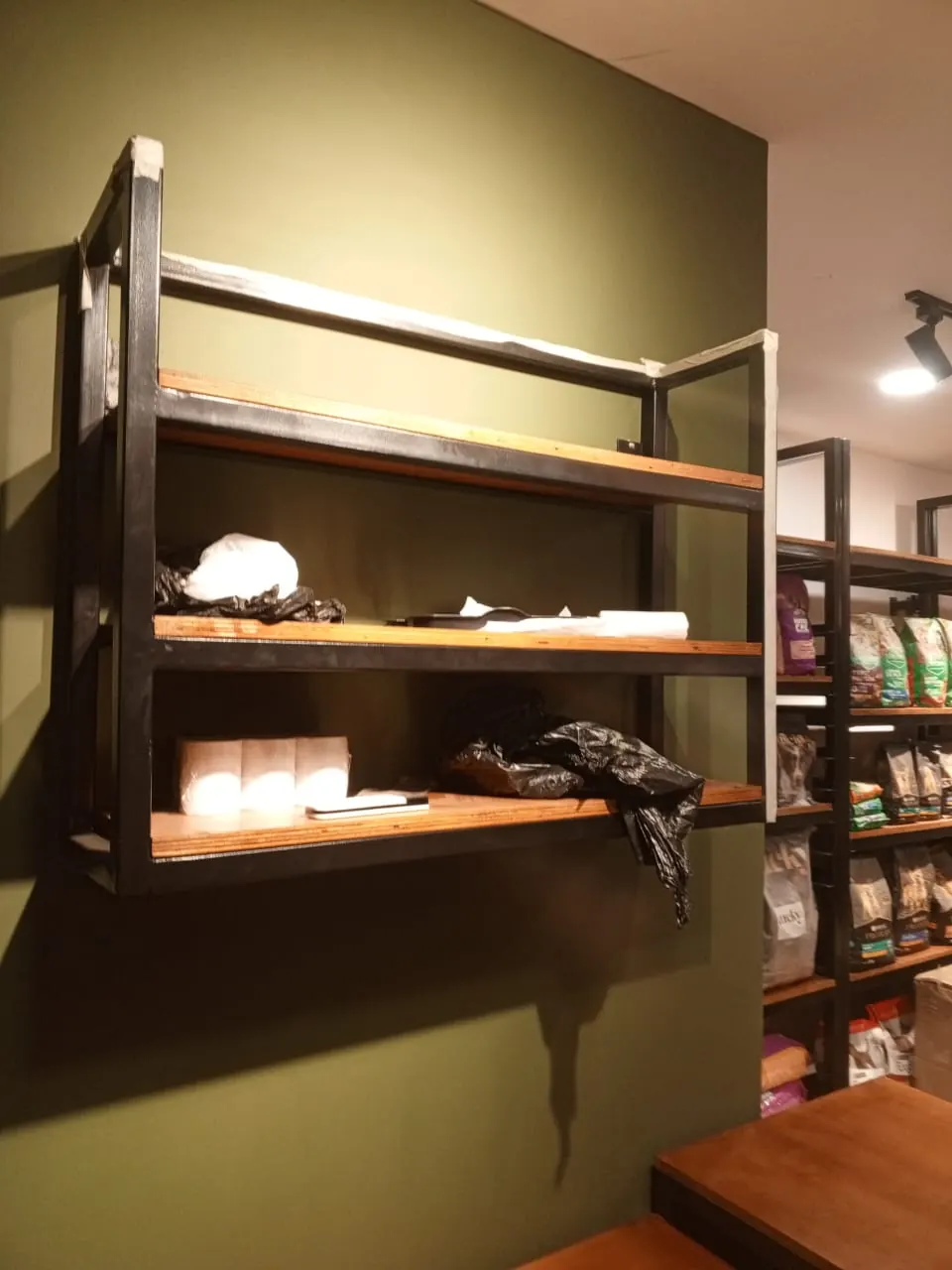 Repisa de pared en acero y madera instalada en tienda de mascotas